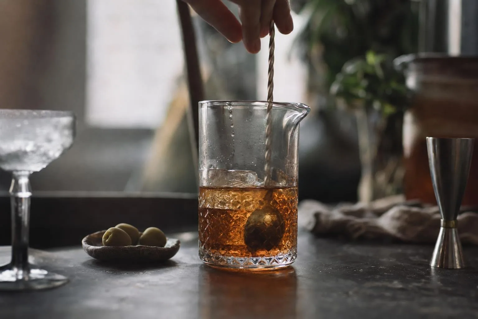 Amber cocktail in a coupe glass on a dark bar top